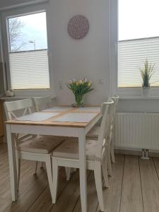 格洛米茨Ferienwohnung Maximilian的白色的餐桌和椅子,上面有鲜花