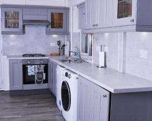 科比5beds-2WC-2shwr-secure 2 van off-road-Biz WiFi-washer-dryer的厨房配有白色橱柜、洗衣机和烘干机