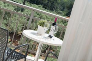 斯卡拉拉乔伊Louloudis Boutique Hotel的阳台上的桌子上摆放着一瓶葡萄酒和玻璃杯