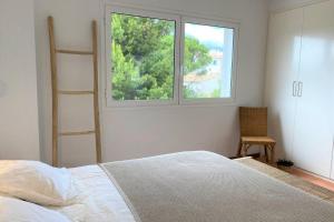 卡达克斯LLEBEIG -Casa mediterránea con gran jardín的一间卧室设有一张床、一个窗口和一把椅子