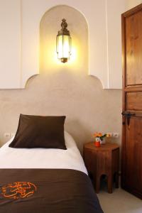 马拉喀什Riad CHERRATA的一间卧室配有一张床、一盏灯和一张桌子