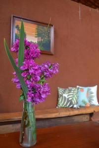 西波山Espaço Mascattes Pousada的花瓶,花朵盛满紫色,坐在桌子上