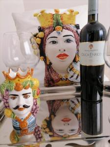 陶尔米纳I TRE CUORI的两座面具的雕像旁边一瓶葡萄酒