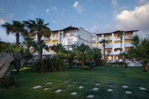 阿兰奇湾城玛格丽特别墅酒店的一座种植了棕榈树的大型白色建筑,位于公园内