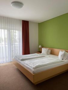 滨湖波德斯多夫Pension Schmidt的一间卧室设有一张大床和绿色的墙壁