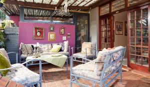 德班Tamarisk Bed & Breakfast的一个带椅子和桌子的庭院和紫色的墙壁