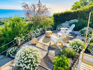 佩塔恰托Residenza B&B VistaMare的花园设有两把白色椅子和鲜花