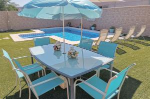 埃斯帕尔蒂纳斯El Capricho de Espartinas的游泳池旁配有桌椅和遮阳伞