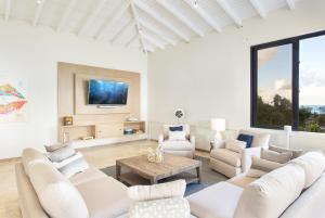 瓦利Sandcastle Beach House的客厅配有白色家具和平面电视