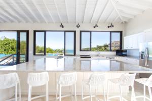 瓦利Sandcastle Beach House的一个带白色椅子的大岛厨房