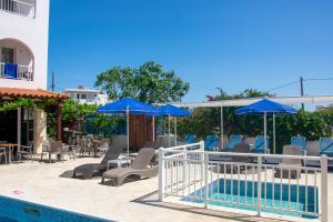 卡尔扎迈纳Harriets Apartments的一个带蓝伞和椅子的庭院和一个游泳池