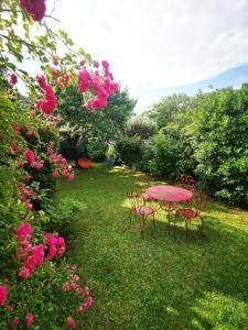 波尔多Dépendance Cosy dans Maison Bordelaise à 200m du tram et du CHU的粉红色的桌子和椅子,在院子里,有粉红色的玫瑰
