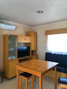 库伊布劳Parque de Campismo da Praia de Pedrogao的客房设有一张木桌、椅子和电视。