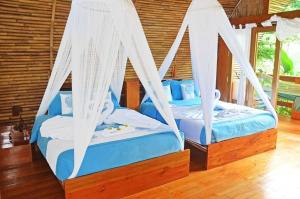 庞岸达兰Lagoona Beach Bungalows - Eco Stay的客房内的2张带白色窗帘的床