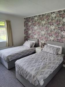 巴利博菲The Bungalow Self-catering Accommodation的一间卧室设有两张床和花卉壁纸