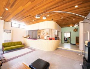 立山町tune Hostel（ツネホステル館山）的一间带绿色沙发的客厅和一间厨房