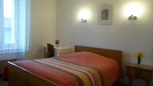 Le Brugeron玫瑰人生酒店的一间卧室配有一张床和一张鲜花桌