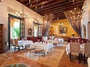 卡塔赫纳索菲特传奇圣克拉拉卡塔赫纳酒店的用餐室配有白色桌椅和吊灯。
