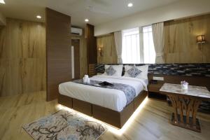艾哈迈达巴德Hotel Elysian Residency的一间卧室配有一张大床和一张桌子