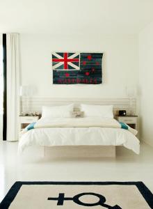 朗布兰奇简易别墅酒店的白色卧室配有一张挂有挂着旗帜的床