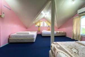 拉瑙OYO HOME 90285 Pogimpaan Homestay的粉红色客房内的三张床