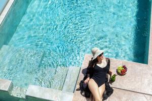 卡尼奥提Sunny Villas Resort & Spa的坐在游泳池旁的戴帽子的女人