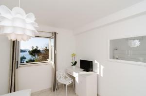 扎通巴比伦旅馆的白色的客房设有一张桌子、一台电视和一个窗户。