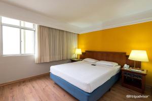 库里提巴Rede Andrade Braz的一间卧室设有一张大床和黄色的墙壁