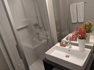 梅拉诺美泉宫酒店的白色的浴室设有水槽和淋浴。