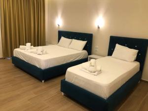卡萨米尔Hotel Adriatik Ksamil的配有白色床单的酒店客房内的两张床