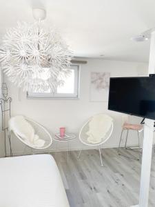 斯普里蒙Appartement Blanc cocooning的客厅配有电视和桌椅