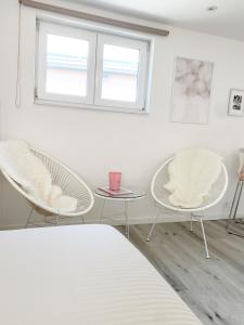 斯普里蒙Appartement Blanc cocooning的一间设有两把椅子、一张桌子和一个窗户的房间