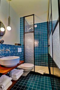 布勒Le Tonnelier的蓝色瓷砖浴室设有卫生间和淋浴。
