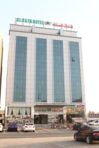 阿尔布亚米Alsafa Hotel的一座大型建筑,前面有汽车停放