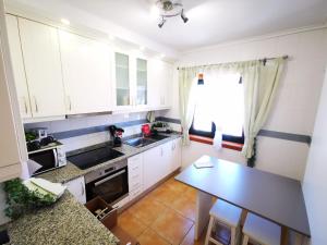 阿威罗Vagueira casa férias的小厨房配有白色橱柜和桌子