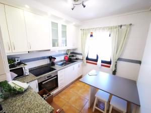 阿威罗Vagueira casa férias的厨房配有白色橱柜和桌子