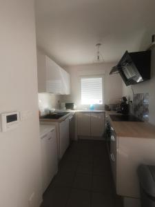 奥内莱沙托Appartement T2 accessible PMR avec terrasse et garage的一间小厨房,配有白色的橱柜和窗户