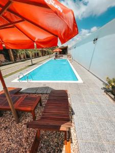 巴雷里尼亚斯Pousada Vasto Horizonte的一个带红色遮阳伞和2个长椅的游泳池