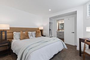 皇后镇Queenstown House Lakeside的卧室配有一张白色大床和一张书桌
