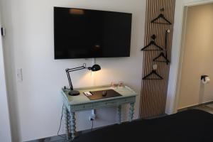 哈泽斯莱乌Hotel Petite B&B的一间房间,墙上设有一张桌子和一台电视