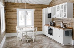 ReuskulaForrest Lodge Karelia的厨房配有白色橱柜和桌椅