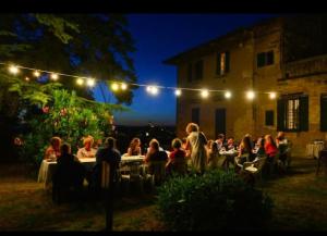 蒙泰斯佩尔托利Agriturismo Le Ginestruzze的一群人晚上坐在花园里的桌子上