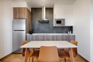 拉科鲁尼亚TH Apartments by Como en Casa的厨房配有桌椅和冰箱。