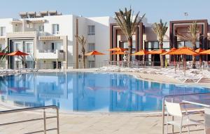 比塞大Andalucia appart hoteL的一个带椅子和橙色遮阳伞的大型游泳池