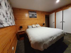 罗托鲁瓦Folia Domus NZ, Redwoods, MBT的一间卧室设有一张大床和木墙