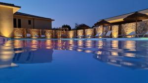 利勒鲁斯Résidence Storia d'Estate的夜间游泳池,配有椅子和遮阳伞