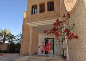托泽尔Maison D'Hôtes villa Fatima的一座建筑的侧面是红花