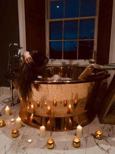 瑟索Forss House的一个人在浴缸里,一边沐浴着蜡烛和一杯葡萄酒
