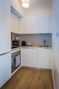 卢加诺Modern apartment in Lugano的厨房铺有木地板,配有白色橱柜。