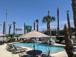 锡布鲁克西布鲁克-NASA-凯马品质酒店及套房的一个带椅子和遮阳伞的游泳池,并种植了棕榈树